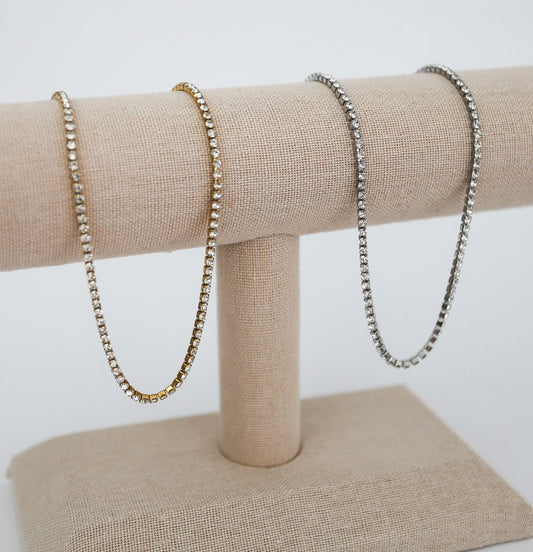 to necklaces hanging next to each other. one is grey on is gold. 